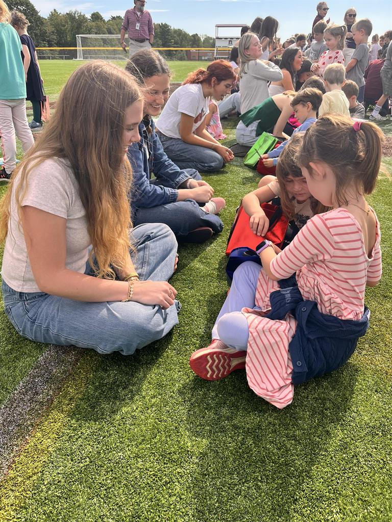 kindergarten students sitting on the ground with seniors