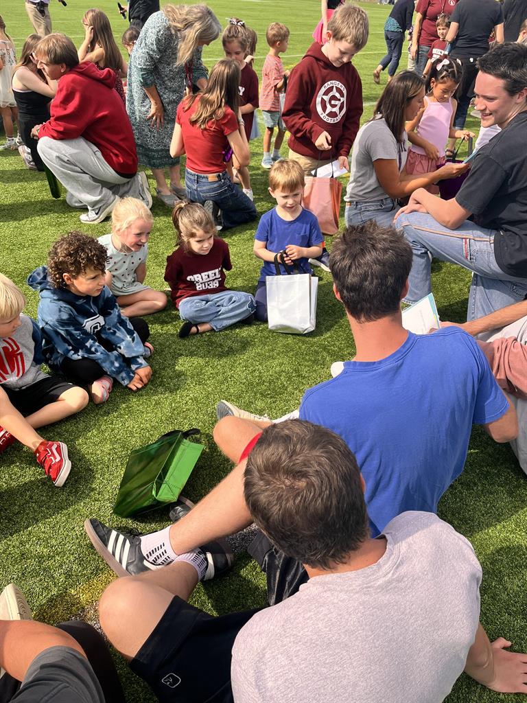 group of MIW and GHS students sitting on the ground during the meeting in the middle event